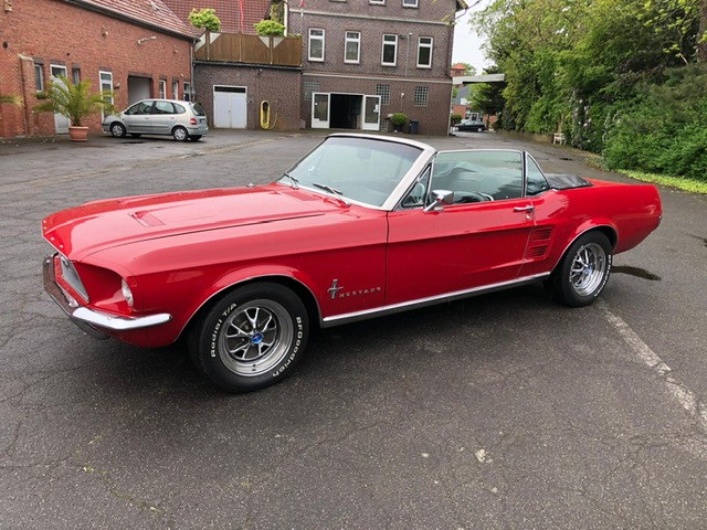 Ford Mustang Cabrio Oldtimer in Rot seitlich links im Hof offenes Verdeck