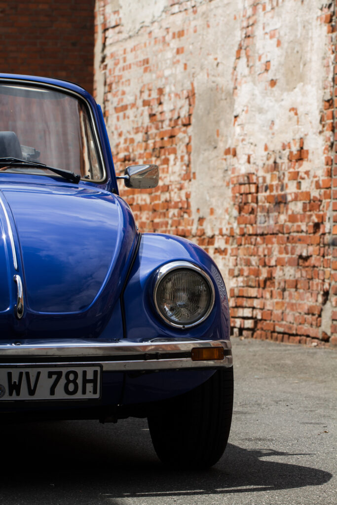 VW Käfer 1303 Cabrio in Blau von vorne neben Backsteinmauer