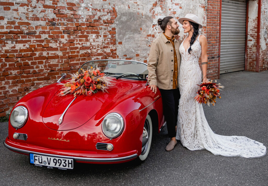 Oldtimer Hochzeit mit Porsche 356 Speedster in Rot mit Brautpaar vor Gemäuer