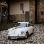Porsche 356 cremeweiß Hochzeitsschmuck auf Kopfsteinpflaster