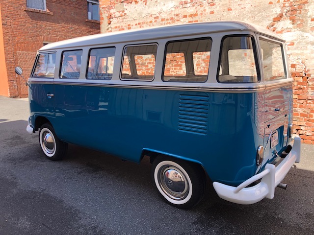 VW Bulli T1 in blau weiß von hinten links vor Backsteinmauer
